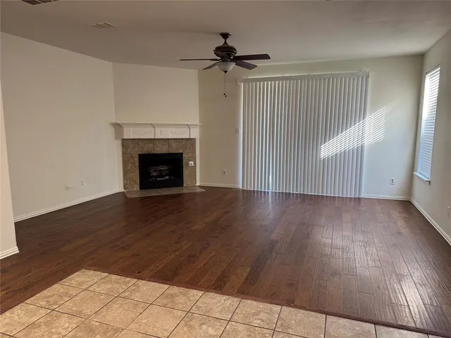 an empty room with wooden floor fireplace and windows