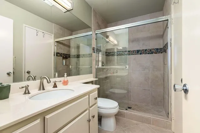 a bathroom with a shower sink vanity mirror and toilet