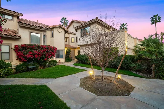 a view of a house with a small yard and a large tree