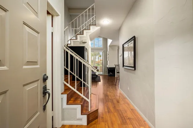 a view of staircase with lots of frames on wall and wooden floor