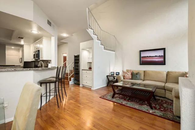 a living room with furniture and kitchen view with wooden floor