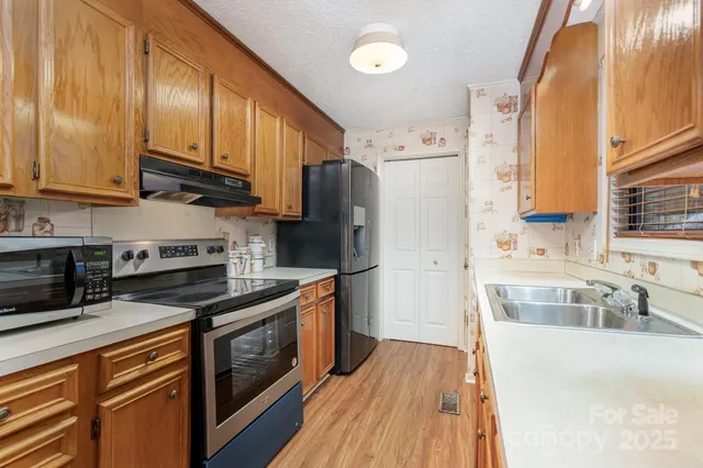 a kitchen with stainless steel appliances granite countertop a refrigerator a stove top oven a sink and dishwasher