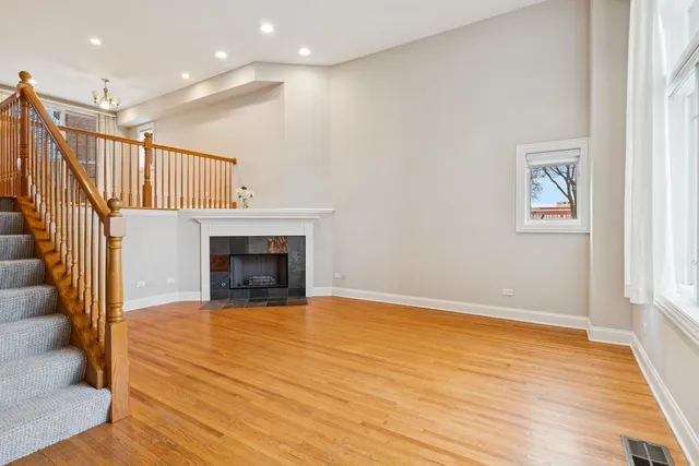 a view of an empty room with wooden floor and a fireplace
