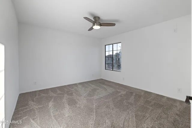 an empty room with a window and a ceiling fan