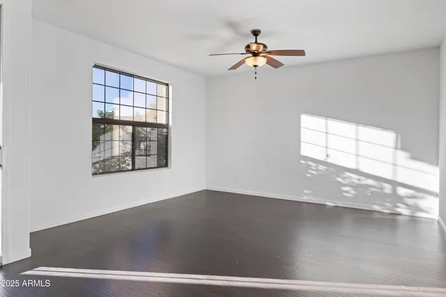 an empty room with wooden floor chandelier fan and windows
