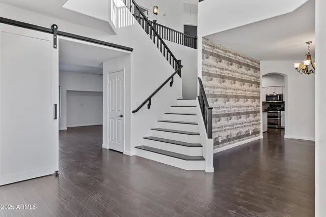 a view of an empty room with wooden floor and stairs
