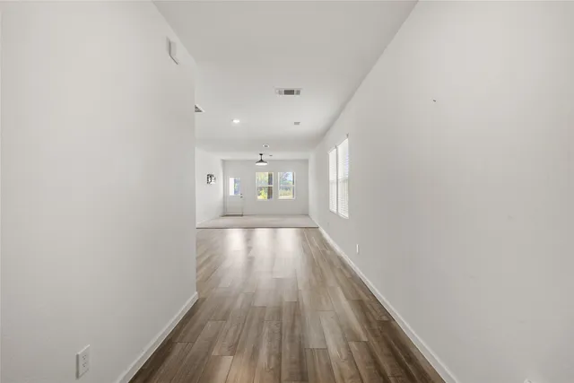 an empty room with windows and ceiling fan