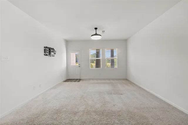an empty room with windows and ceiling fan
