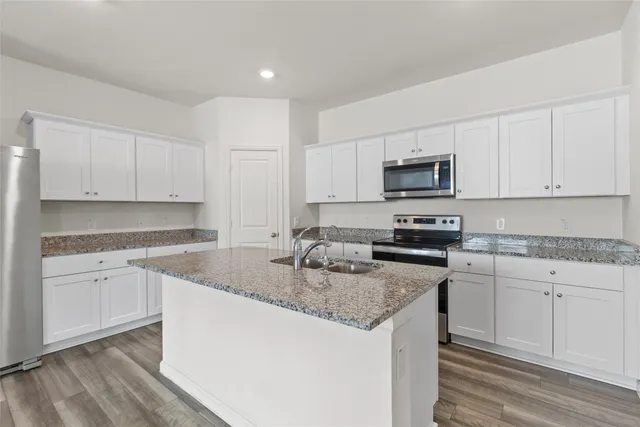 a kitchen with granite countertop a sink stove and white cabinets