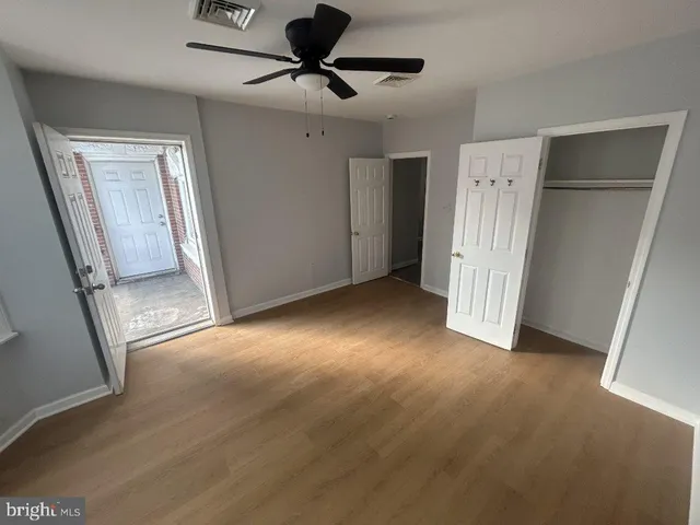 a view of empty room with wooden floor and fan