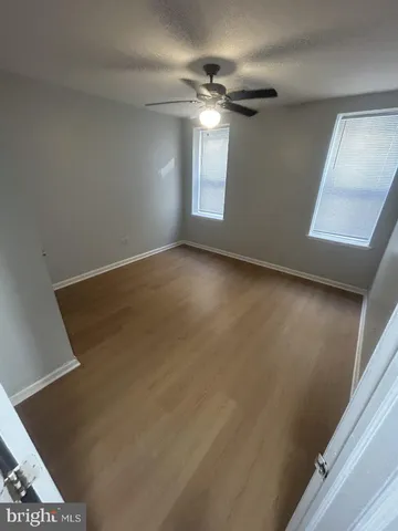 en empty room with windows and ceiling fan
