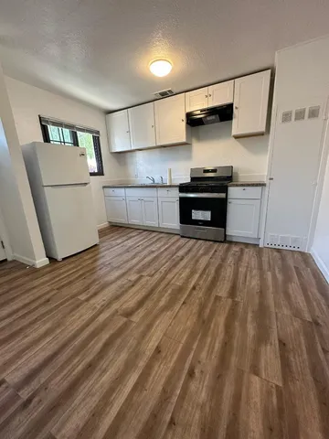 a kitchen with granite countertop a refrigerator and a stove top oven