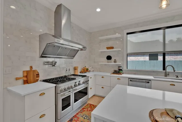 a kitchen with stainless steel appliances a sink a stove and a large window
