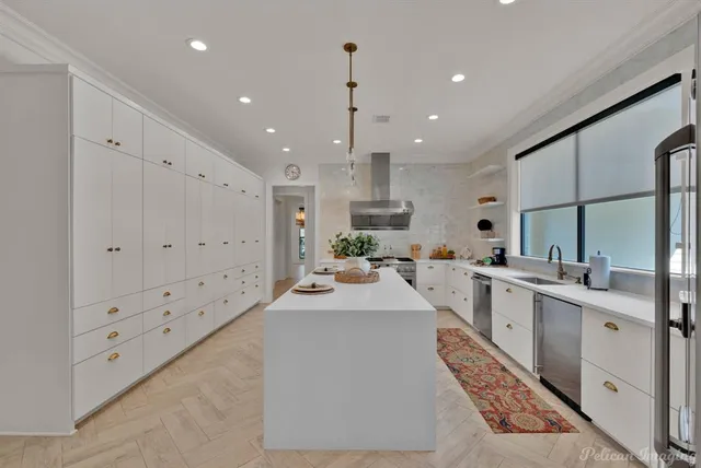 a large white kitchen with lots of counter space sink and appliances
