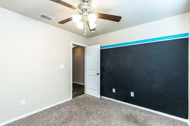 an empty room with a ceiling fan and a bathroom