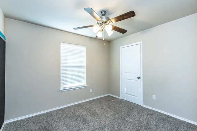an empty room with window and ceiling fan