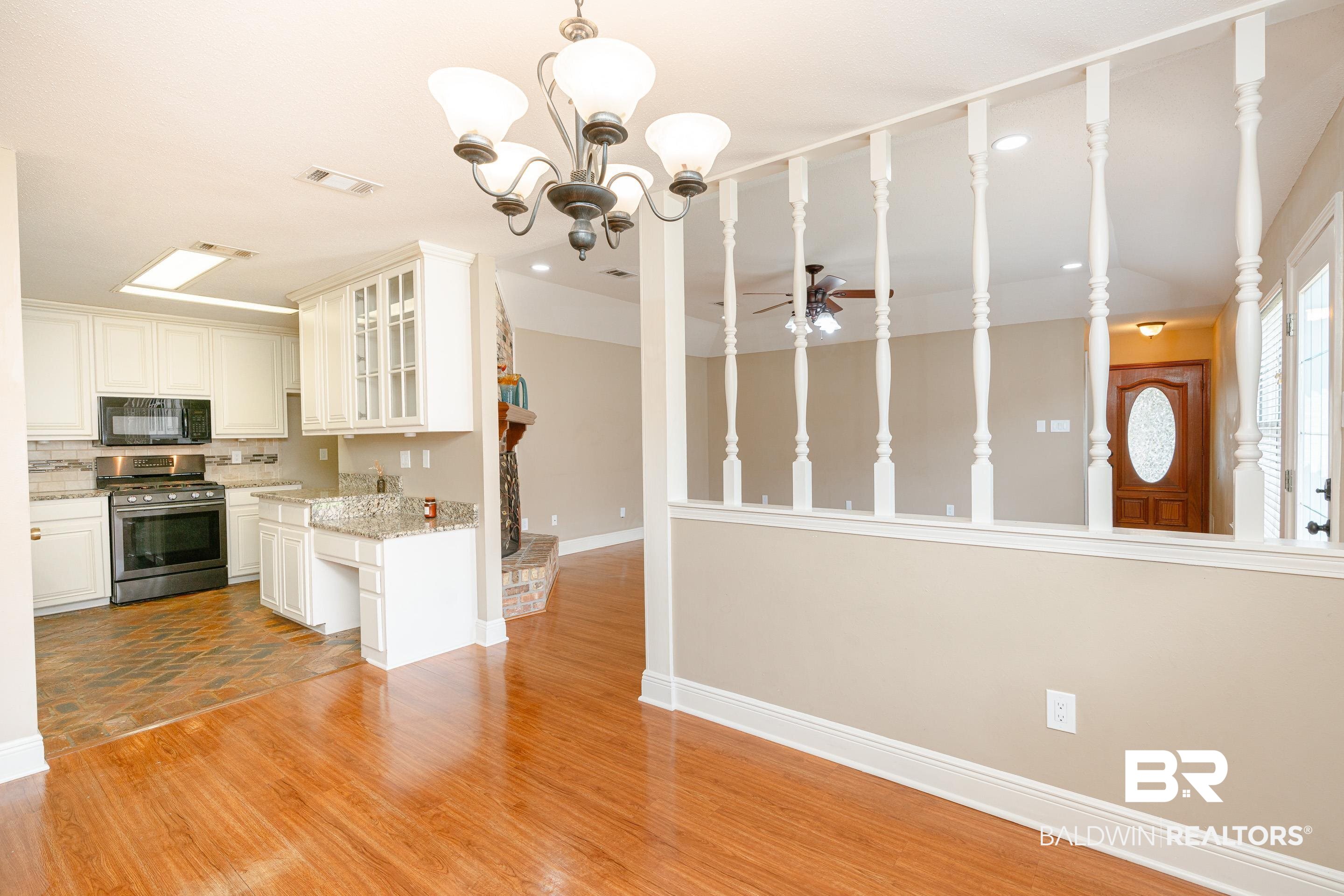 23 Old Mill Court Mobile, AL 36608 - Photo 11 of 37 Kitchen featuring white cabinets, decorative light fixtures, stainless steel gas range, light wood-type flooring, and ceiling fan with notable chandelier