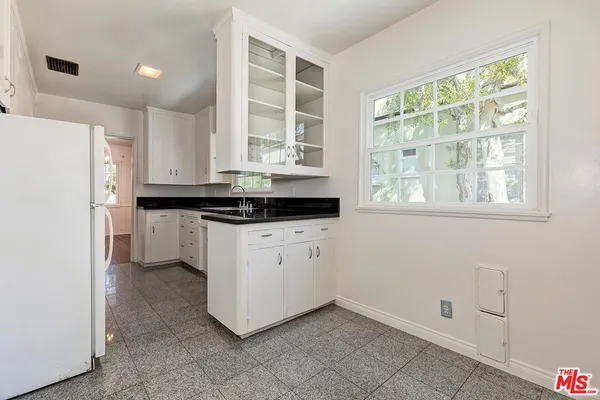 a kitchen with a refrigerator and white cabinets