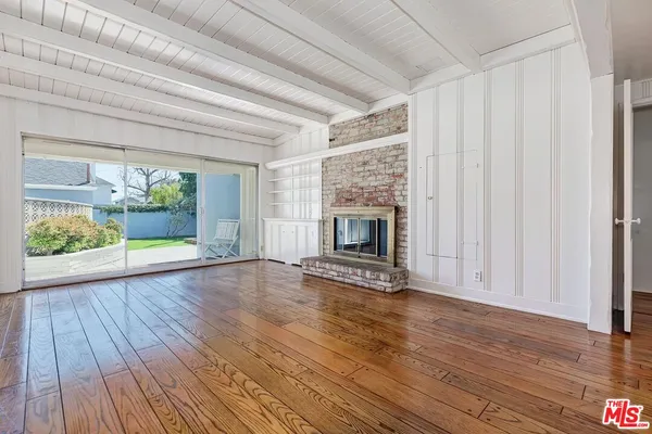 a view of an empty room with wooden floor fireplace and a window
