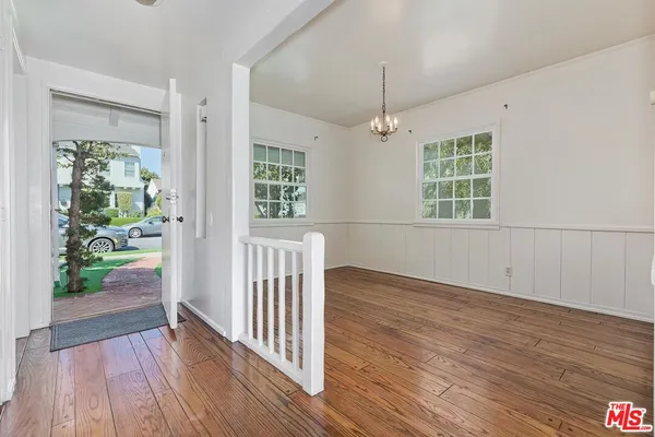 an empty room with wooden floor a chandelier and windows