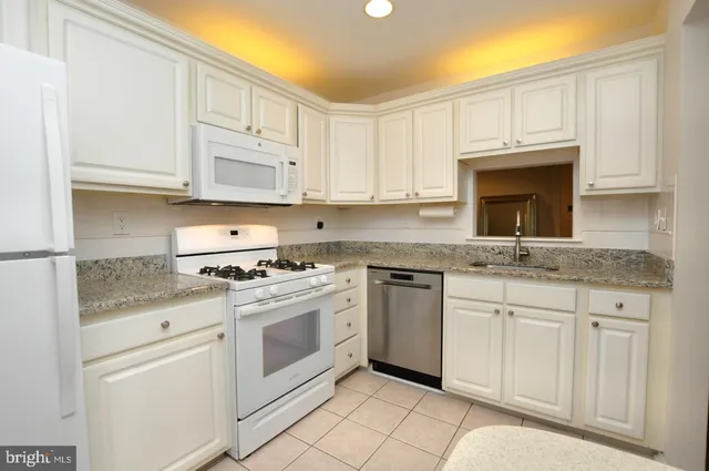 a kitchen with granite countertop white cabinets and white appliances