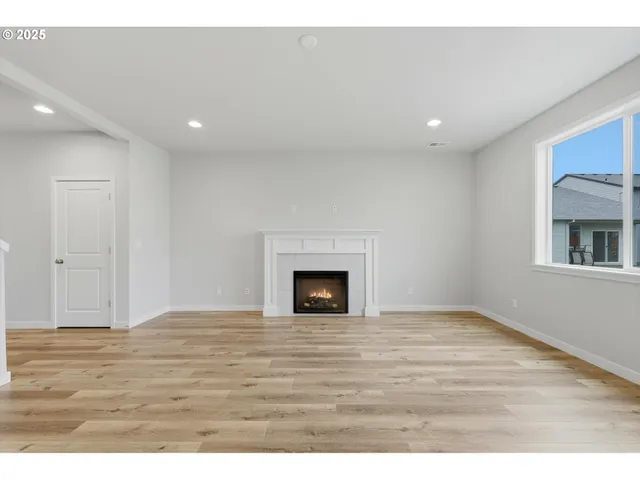 a view of empty room with wooden floor and fireplace