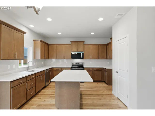 a large kitchen with a sink and dishwasher a oven with wooden cabinets