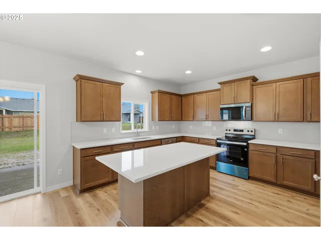 a kitchen with stainless steel appliances granite countertop a sink a stove top oven a counter space and cabinets