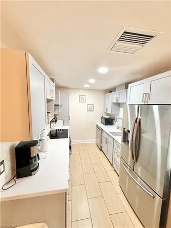 a kitchen with a refrigerator a stove top oven and a sink with wooden floor