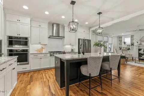 a kitchen with kitchen island granite countertop a dining table chairs and white cabinets