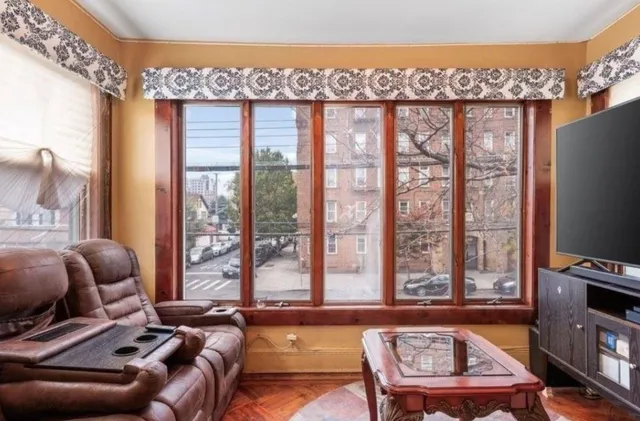 a living room with furniture a flat screen tv and a floor to ceiling window