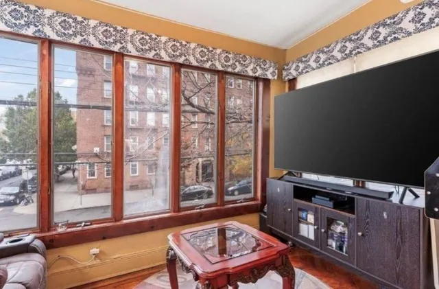 a living room with furniture a flat screen tv and a floor to ceiling window