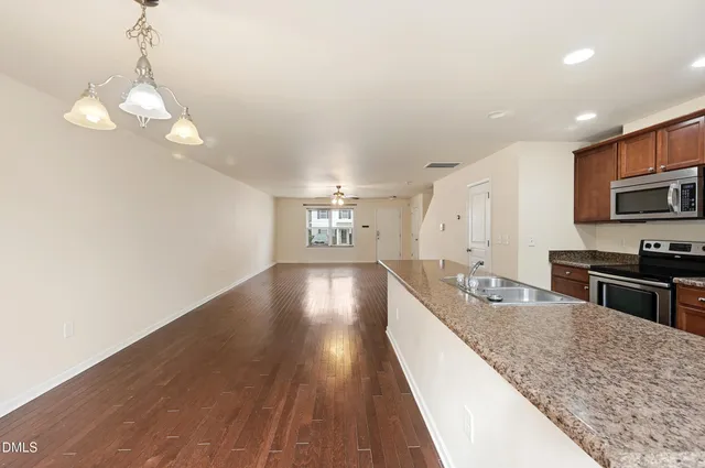 a kitchen with stainless steel appliances granite countertop a sink a stove top oven a counter space and cabinets