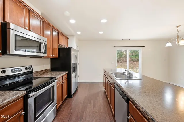 a kitchen with stainless steel appliances granite countertop a stove a sink and a refrigerator