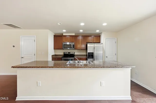 a kitchen with kitchen island granite countertop a stove top oven a sink and a granite counter tops