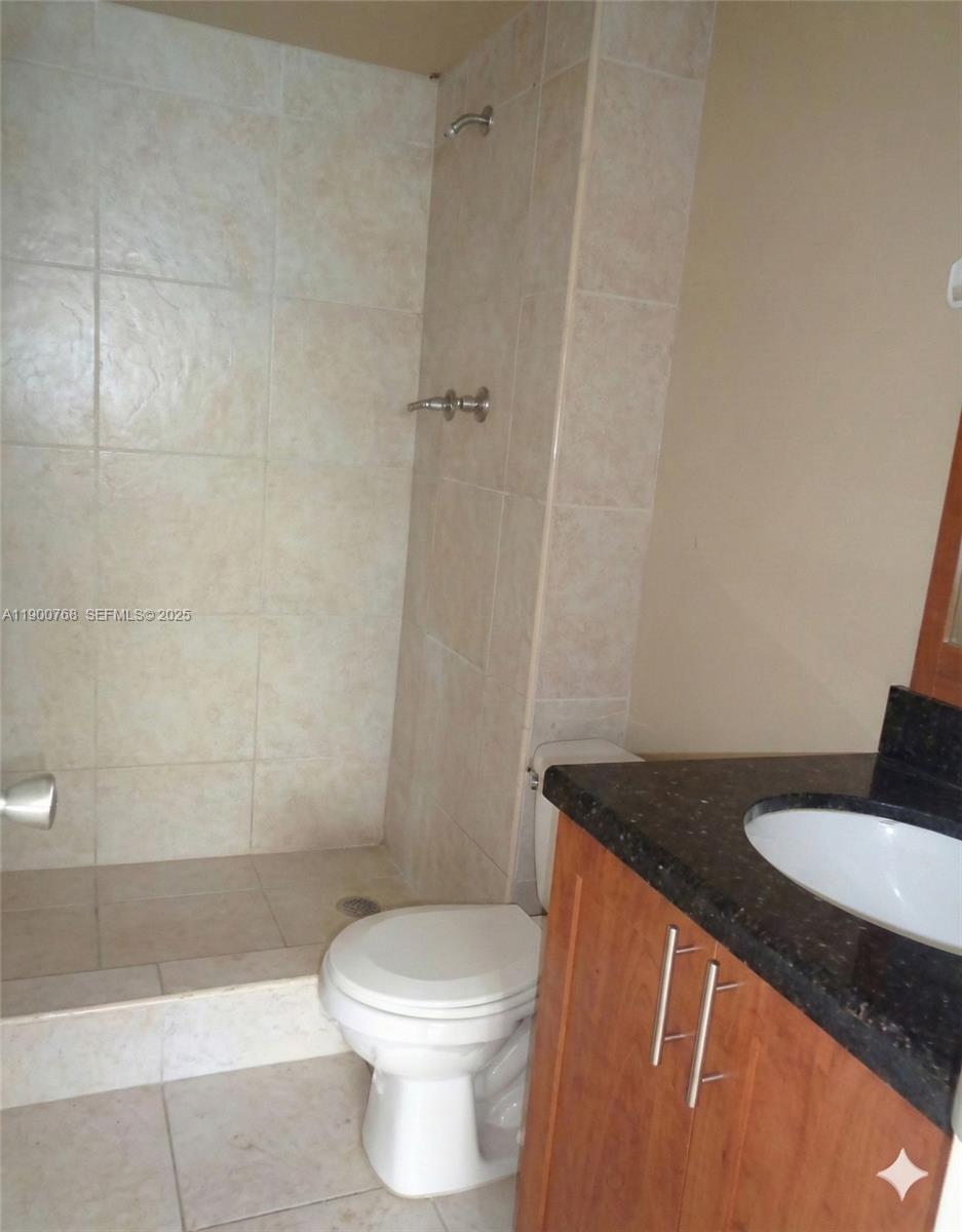 494 Northwest 165th Street, Unit C602 Miami, FL 33169 - Photo 12 of 12 a bathroom with a granite countertop sink toilet and shower
