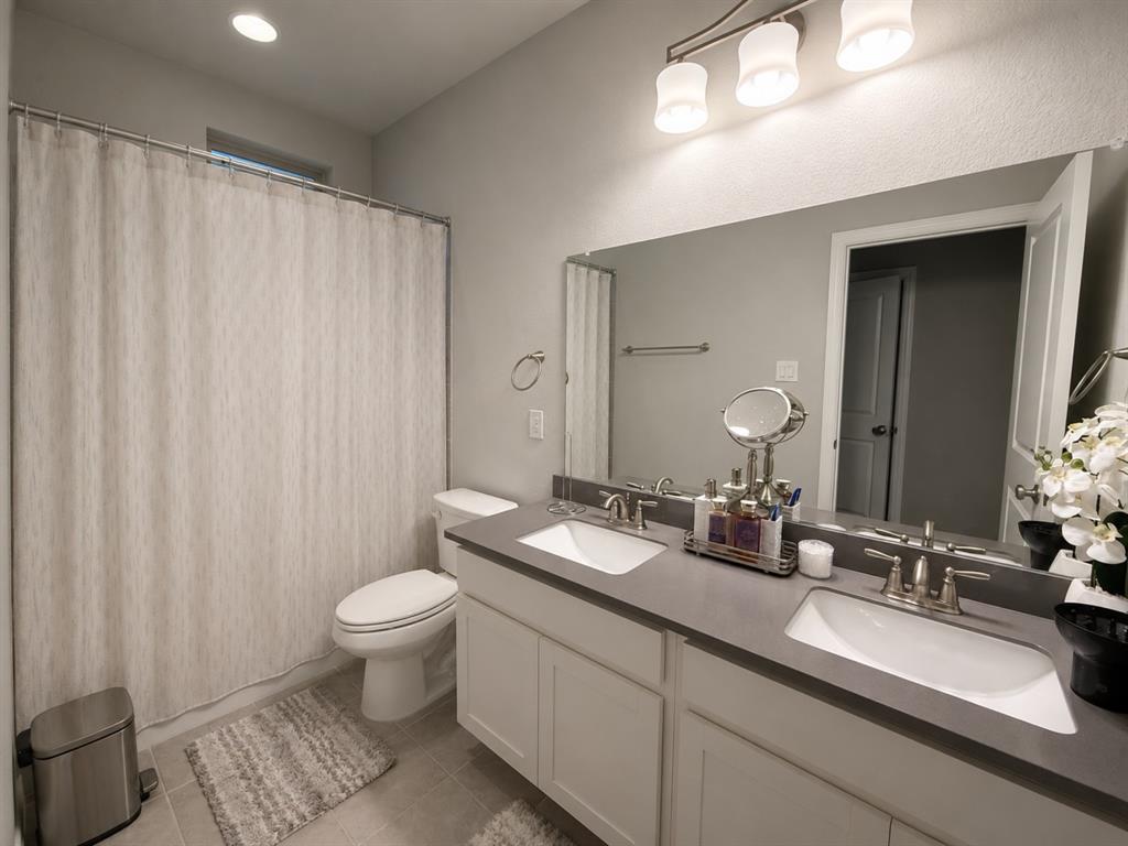 8235 Snapdragon Way Dallas, TX 75252 - Photo 20 of 29 Bathroom featuring a dual vanity with undermount sinks, a long mirror, and a shower/tub combination