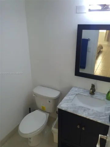 a bathroom with a granite countertop toilet sink and mirror