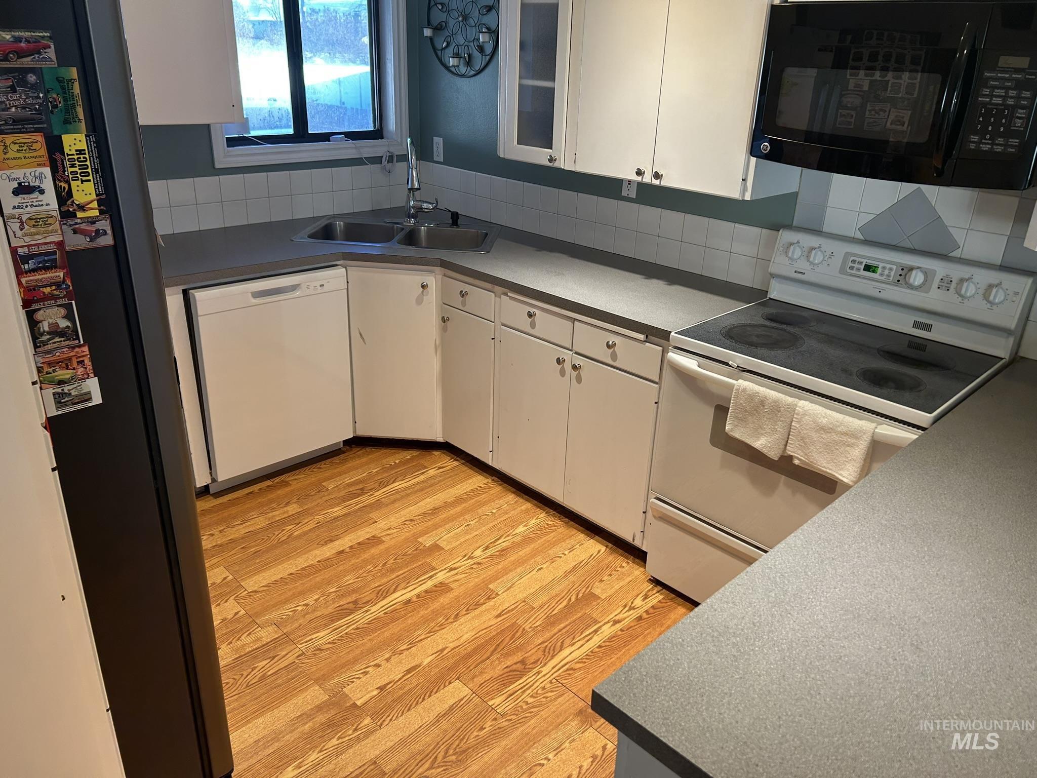 3731 16th Street Lewiston, ID 83501 - Photo 15 of 35 Kitchen with black appliances, white cabinets, light wood finished floors, and decorative backsplash