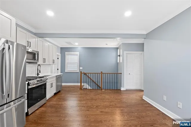 a kitchen with stainless steel appliances a refrigerator and wooden floor