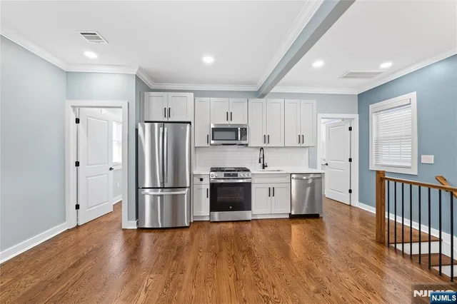 a kitchen with cabinets stainless steel appliances and wooden floor