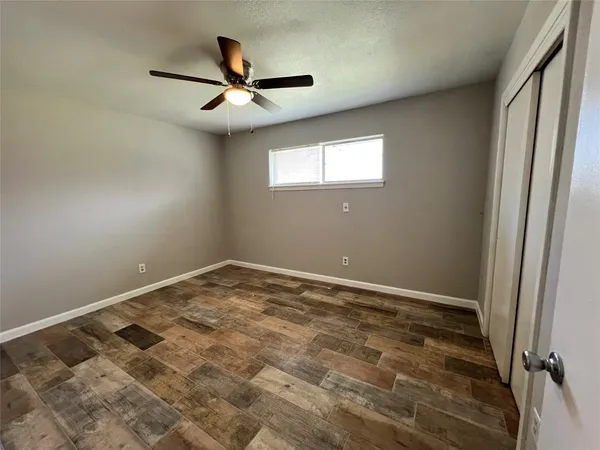 an empty room with ceiling fan and window