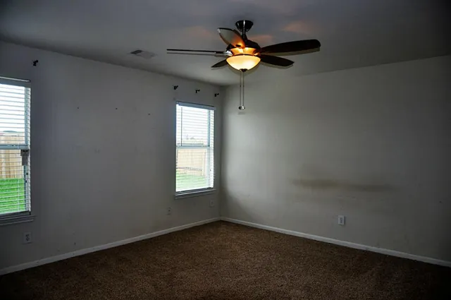 an empty room with a window and a fan