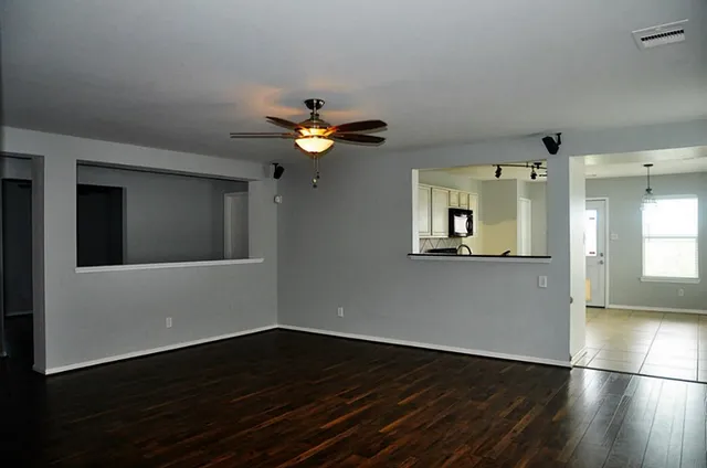 a view of an empty room with wooden floor and a window