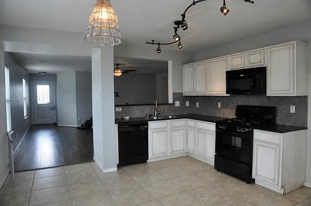 a kitchen with granite countertop a stove a sink and a microwave