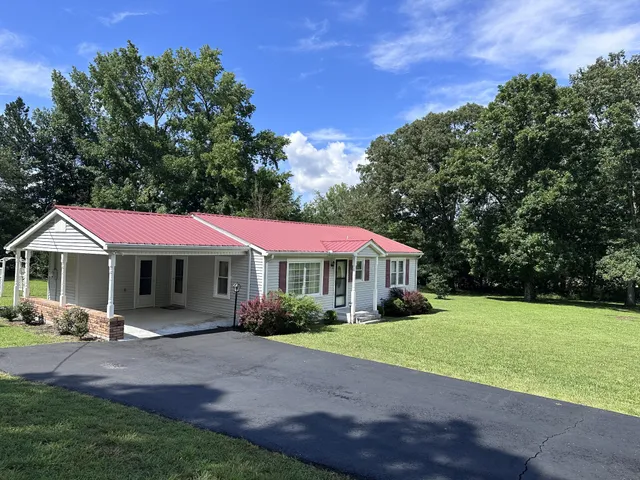 a front view of a house with a garden and trees