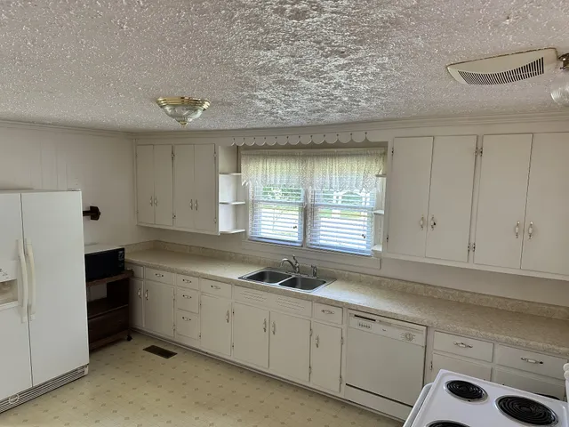a kitchen with granite countertop white cabinets and white appliances