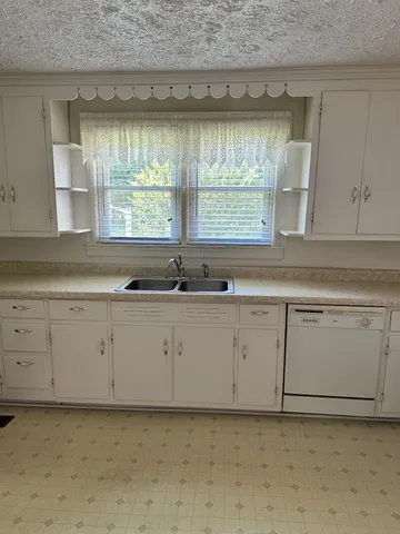 a kitchen with granite countertop white cabinets white appliances and a sink