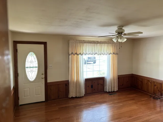 an empty room with wooden floor mirror and windows