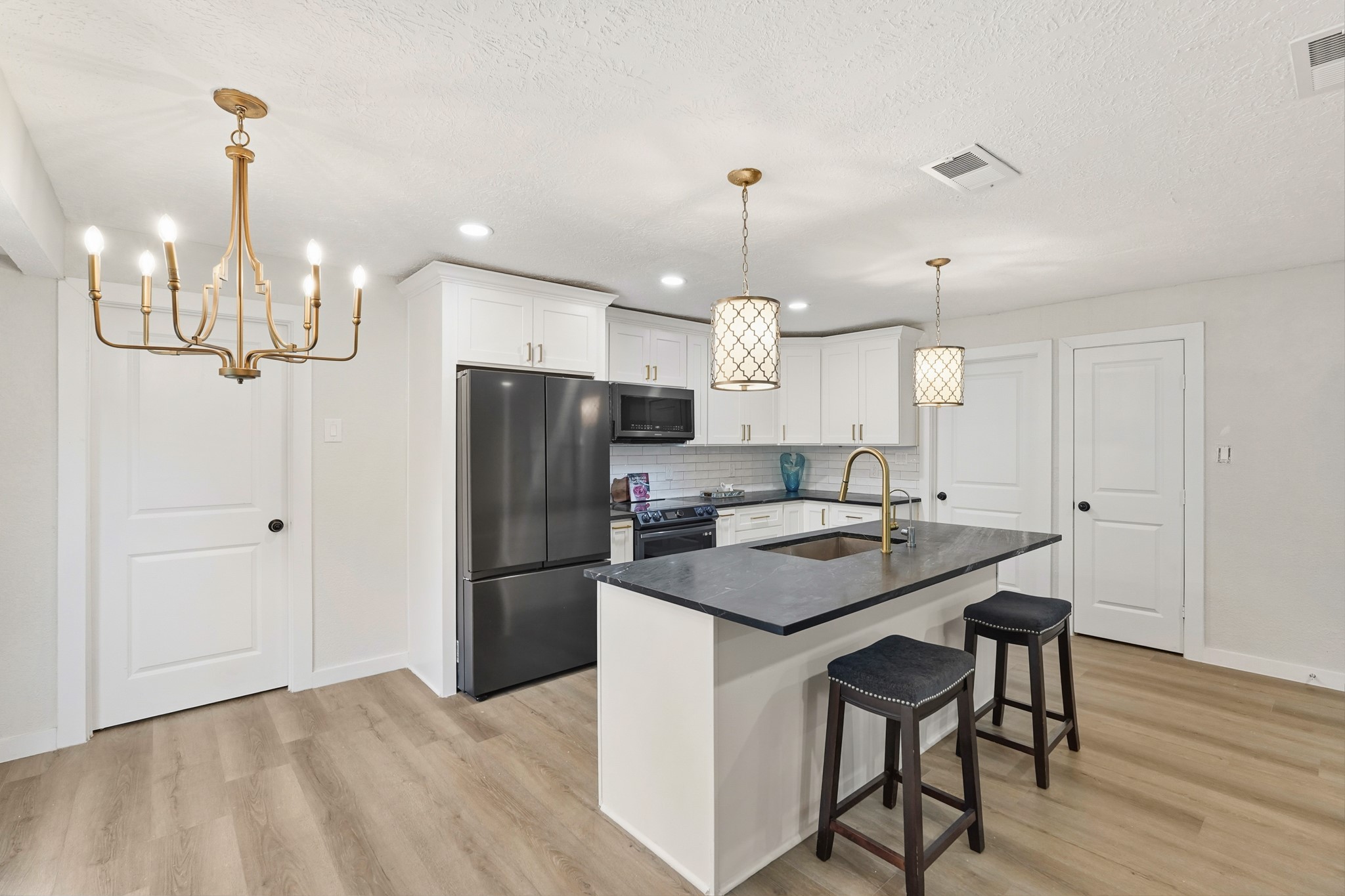 24006 Crooked Creek Road Hockley, TX 77447 - Photo 10 of 25 a kitchen with stainless steel appliances kitchen island granite countertop a refrigerator a stove and white cabinets with wooden floor